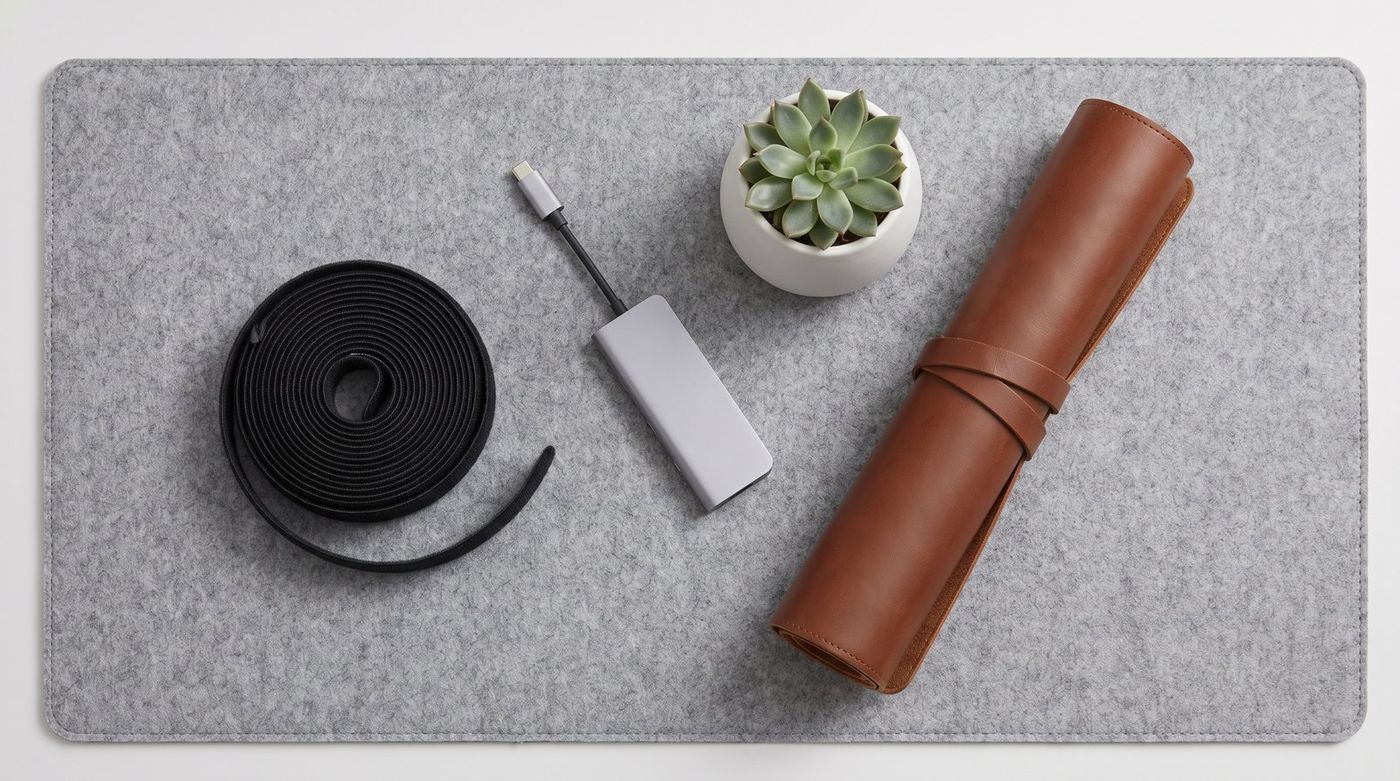 Flat lay of small desk setup gifts on a felt mat: cable ties, a USB-C hub, a small plant in a ceramic pot
