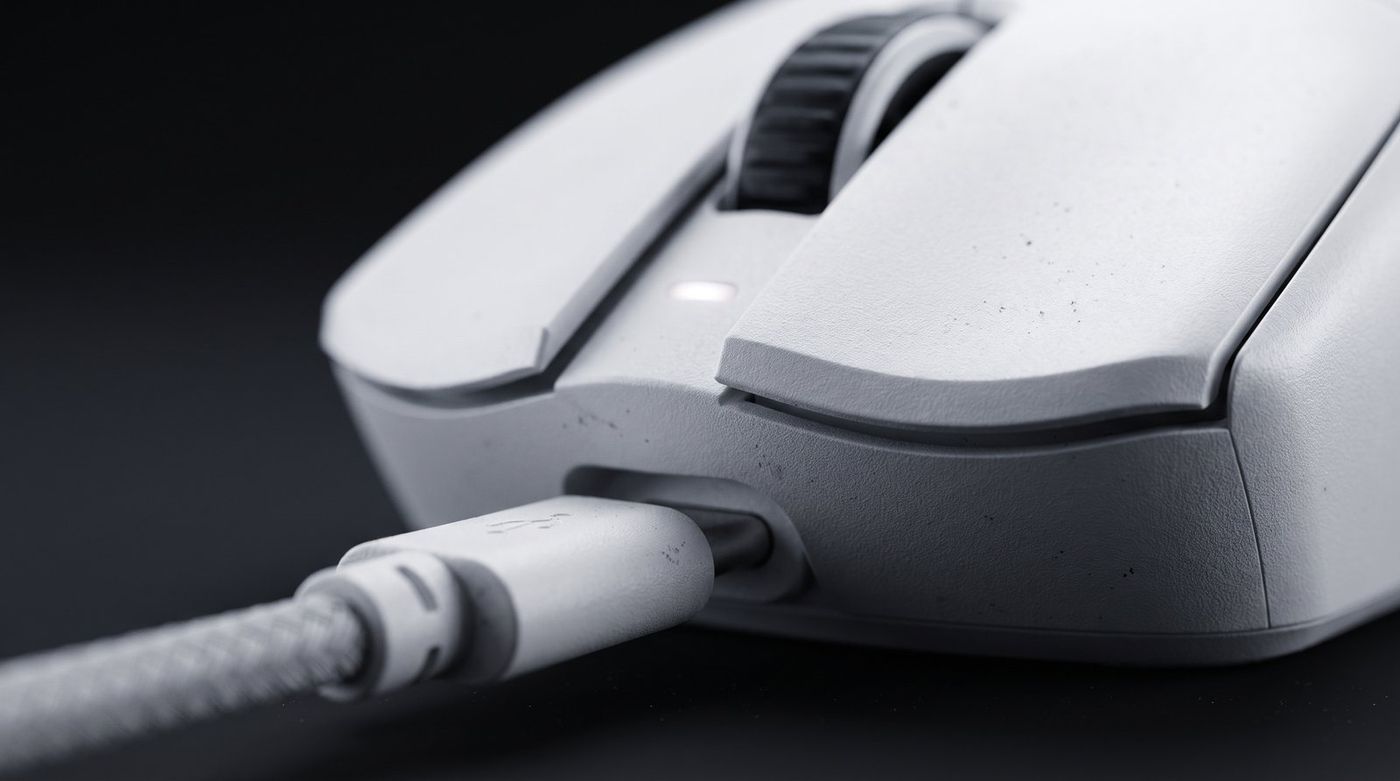 Close-up of a wireless gaming mouse charging port with a USB-C cable plugged in, shallow depth of field